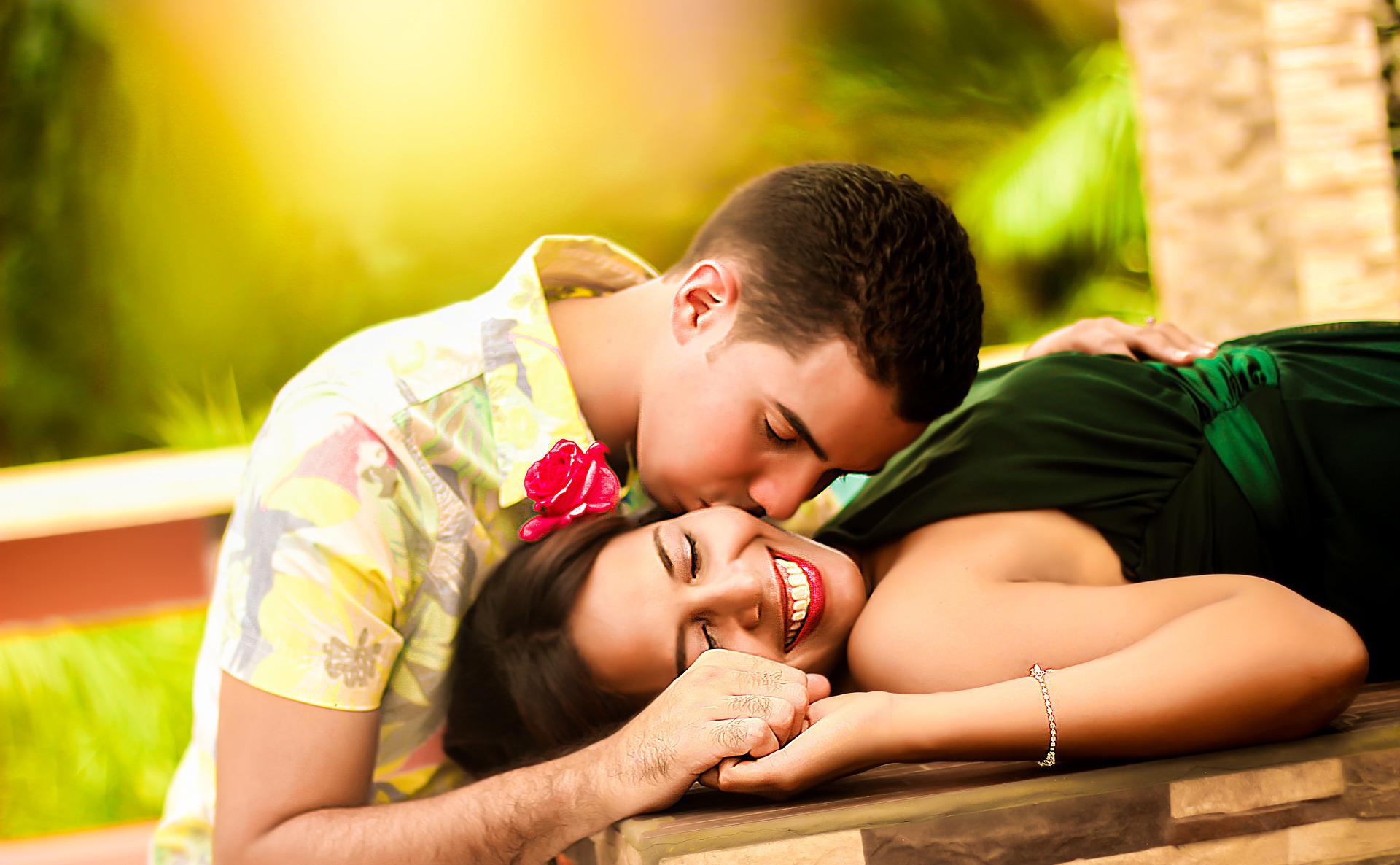 A man kissing his girlfriend lying on a wooden table