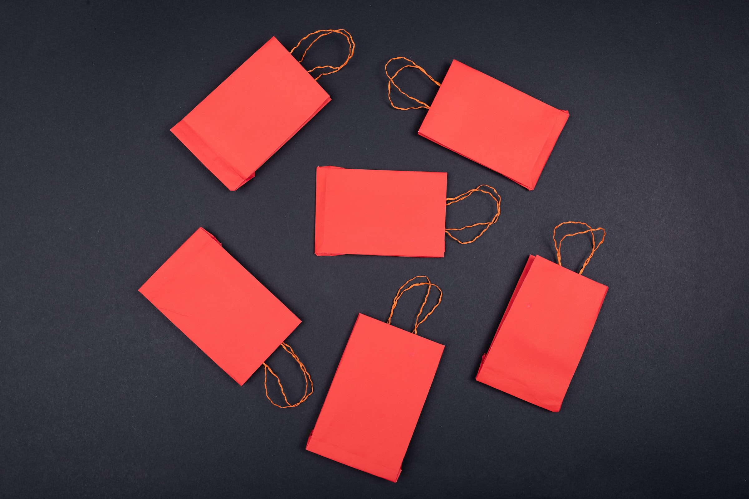 Six red shopping bags over a black desk