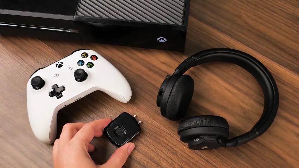 White Xbox One controller and black headphones on a wooden table