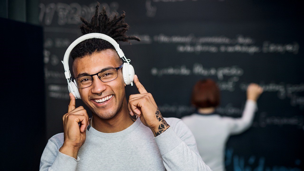 A man wearing headphones is smiling.